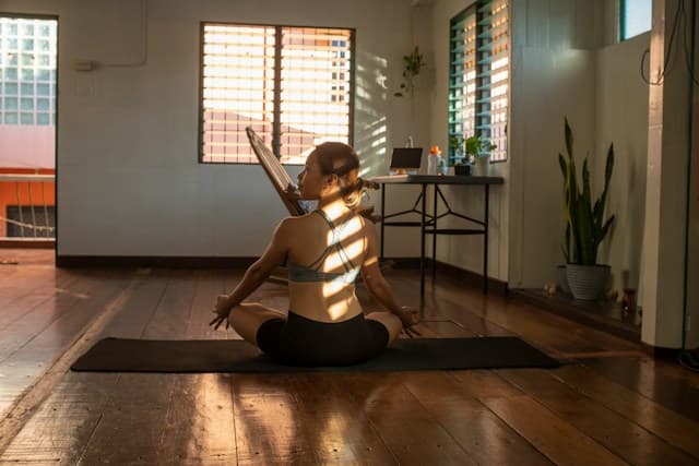 Woman meditating on a mat in warm afternoon light